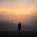 A misty landscape with a lone figure walking.